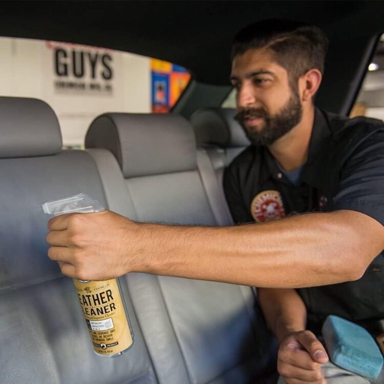 Muškarac koristi Chemical Guys Leather Cleaner sprej za čišćenje zadnjih kožnih sedišta u automobilu.