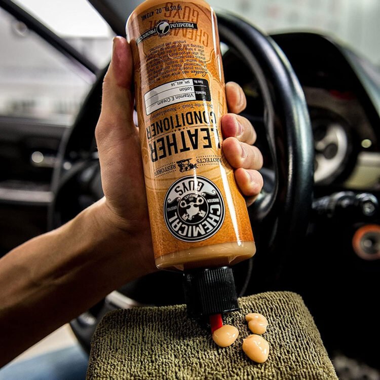 Prikaz nanošenja Chemical Guys Leather Conditioner sredstva na braon mikrofiber aplikator u automobilu.