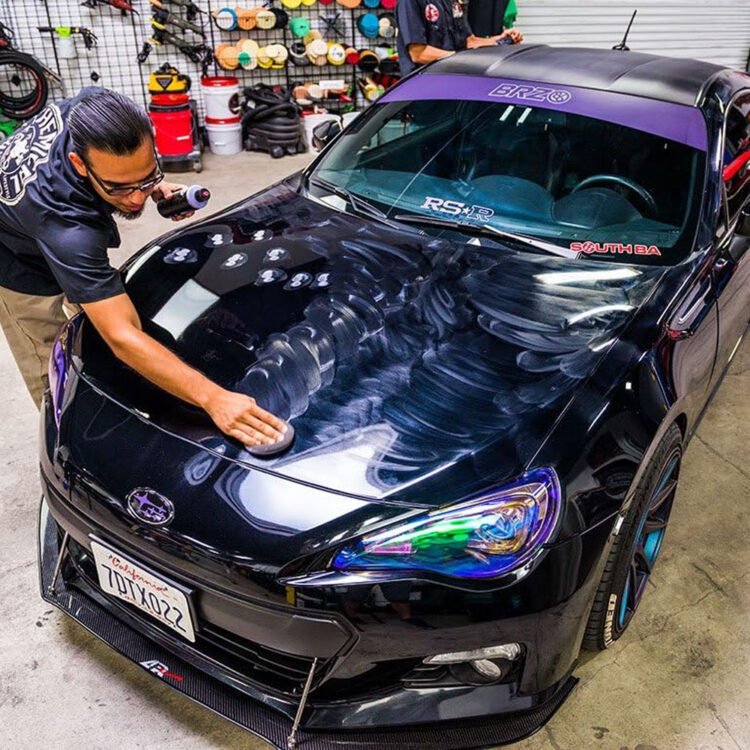 Osoba nanosi vosak Chemical Guys Black Light na crni automobil.