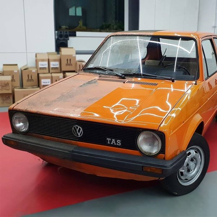 Golf 1 TAS narandžaste boje ispoliran do pola, druga polovina pokrivena u mahovini i prašini.